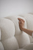 Hand touching a textured white Fabric on a sofa