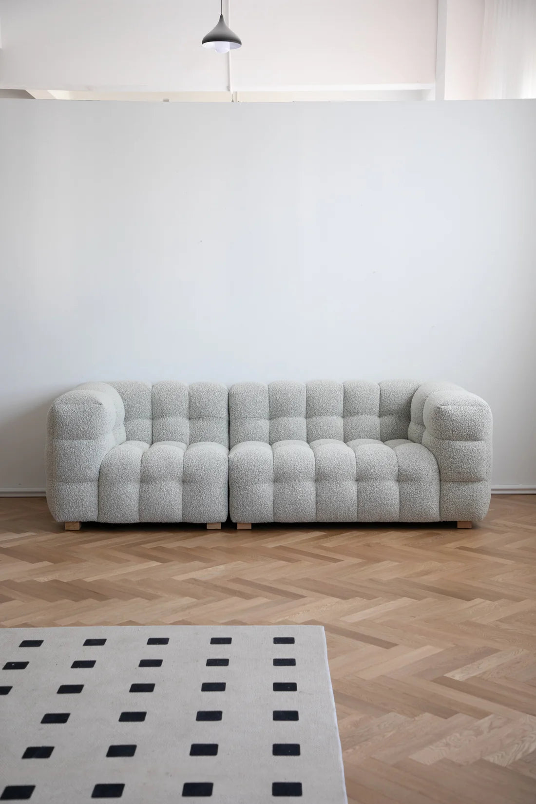Gray love seat sofa in a room with a white wall and wooden floor.