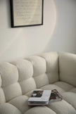 Beige reclining sofa with a magazine on it, framed text on the wall.