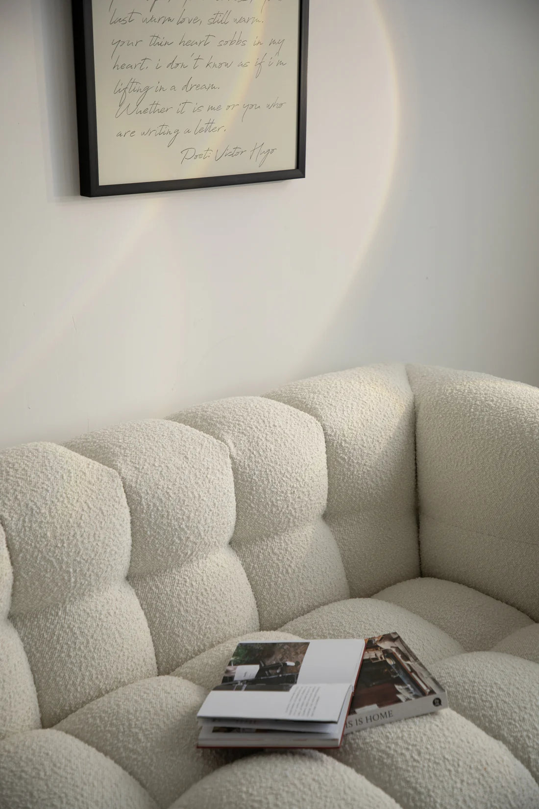 Beige reclining sofa with a magazine on it, framed text on the wall.