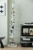 Tall white metal display corner storage shelf with decorative items next to a television on a stand.