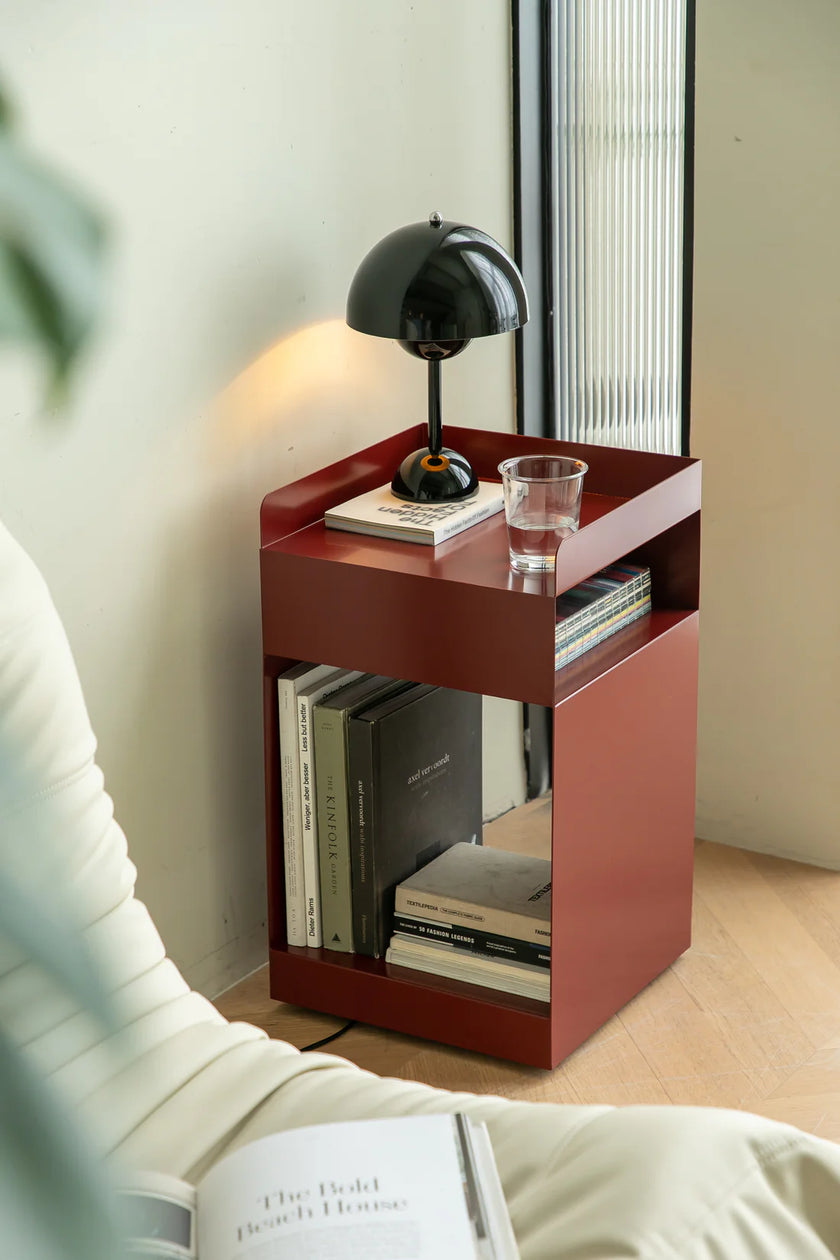 Small red sofa side table with books and a glass in a room setting