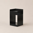 Black metal side table on a beige background