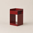 Red metal side table on a beige background