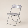 Clear plastic folding chair with metal frame on a beige background