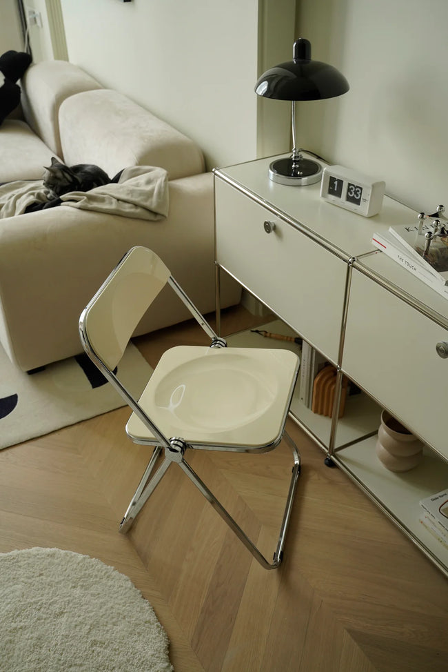 Modern living room with a white folding chair, sofa, and side table.