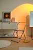 Modern room with a folding chair, shelf, and abstract art on a wall.