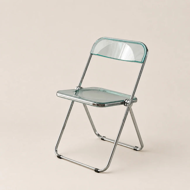 Clear glass folding chair with metal frame on a beige background