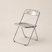 Clear plastic folding chair with metal frame on a beige background