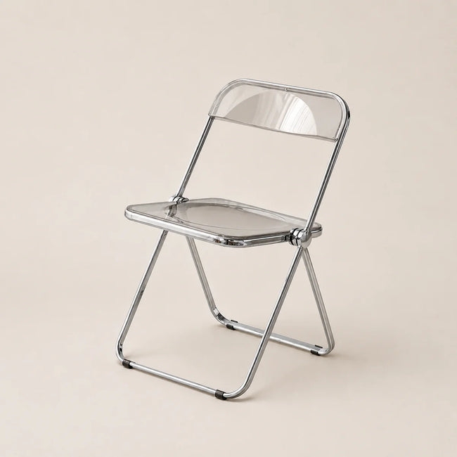 Clear plastic folding chair with metal frame on a beige background