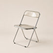 Clear plastic folding chair with metal frame on a beige background