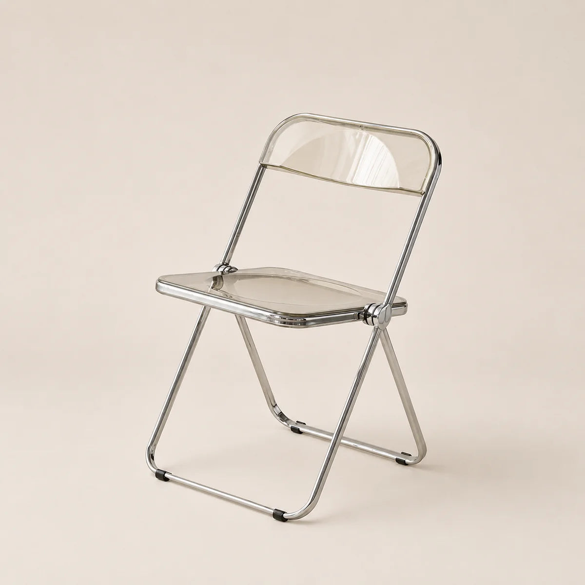 Clear plastic folding chair with metal frame on a beige background