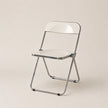 Clear plastic folding chair with metal frame on a beige background