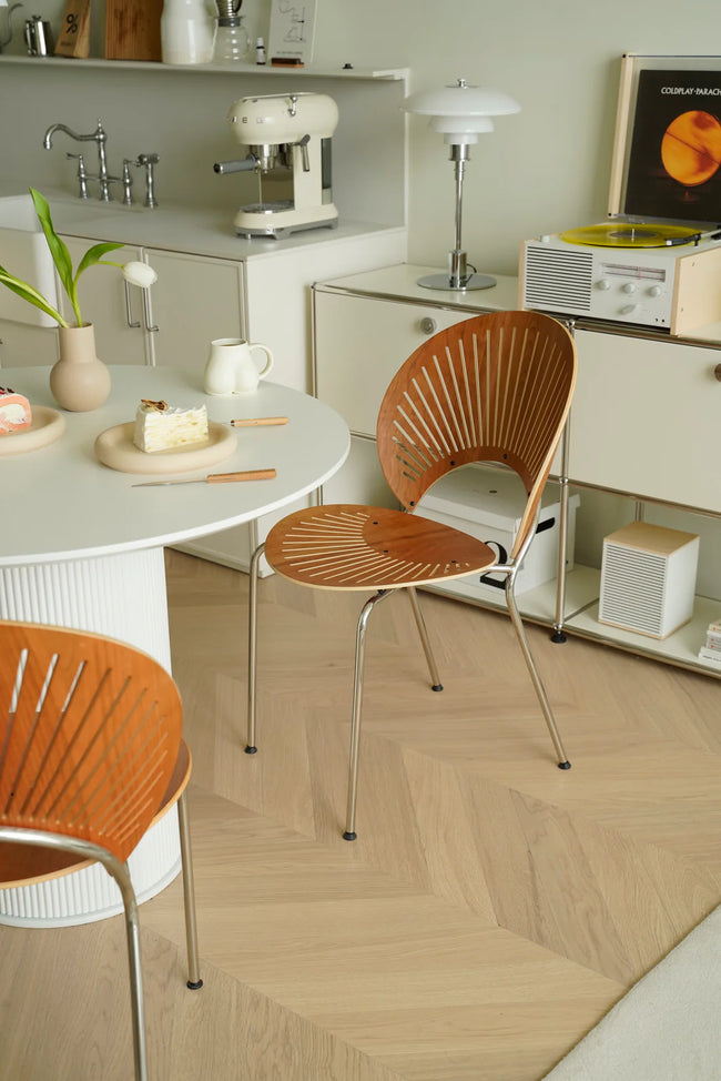 Modern kitchen with wooden living room chairs, white countertops, and vintage appliances.