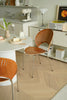 Modern kitchen with wooden living room chairs, white countertops, and vintage appliances.