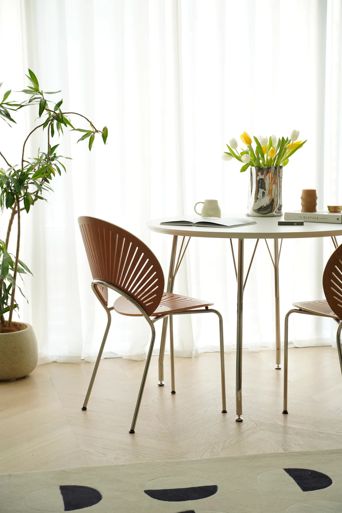 Modern dining area with a table and wooden chairs in a bright room.