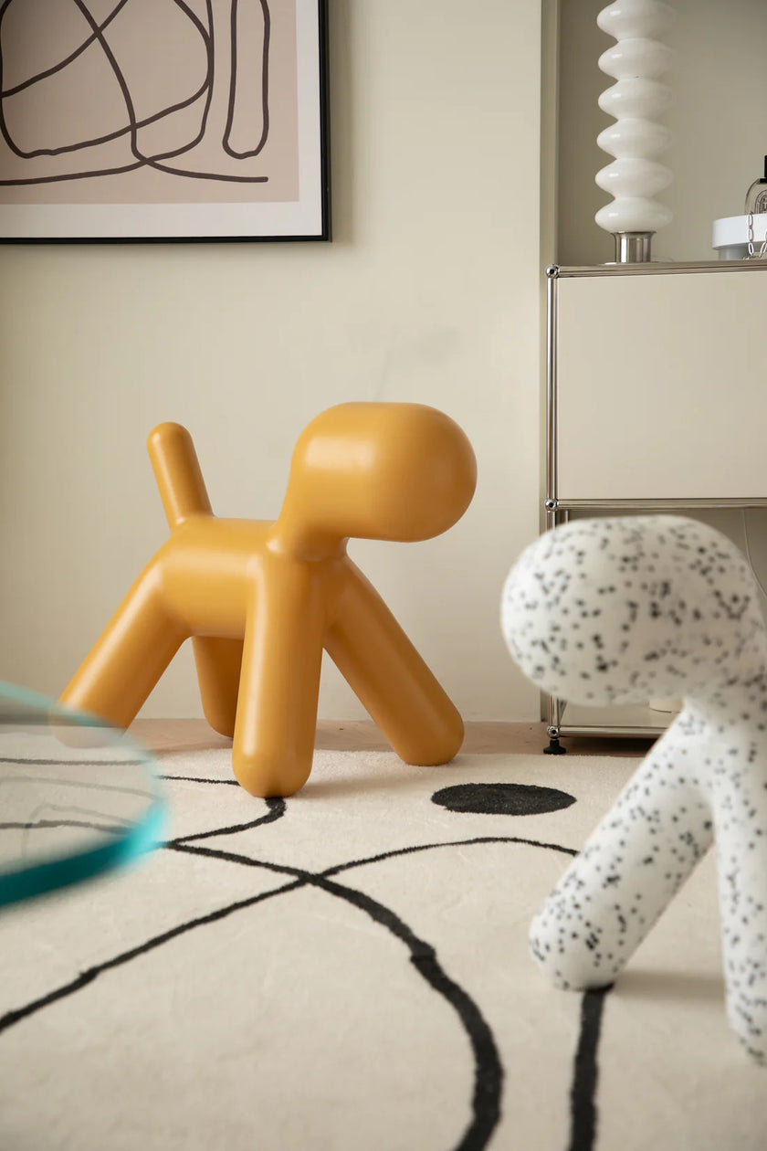 Two unique plastic kids chairs, one orange and one white with black speckles, in a room with abstract art on the wall.