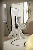 White dog-shaped plastic toddler chair with black spots  on a rug in a modern living room.