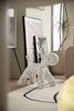 White dog-shaped plastic toddler chair with black spots  on a rug in a modern living room.