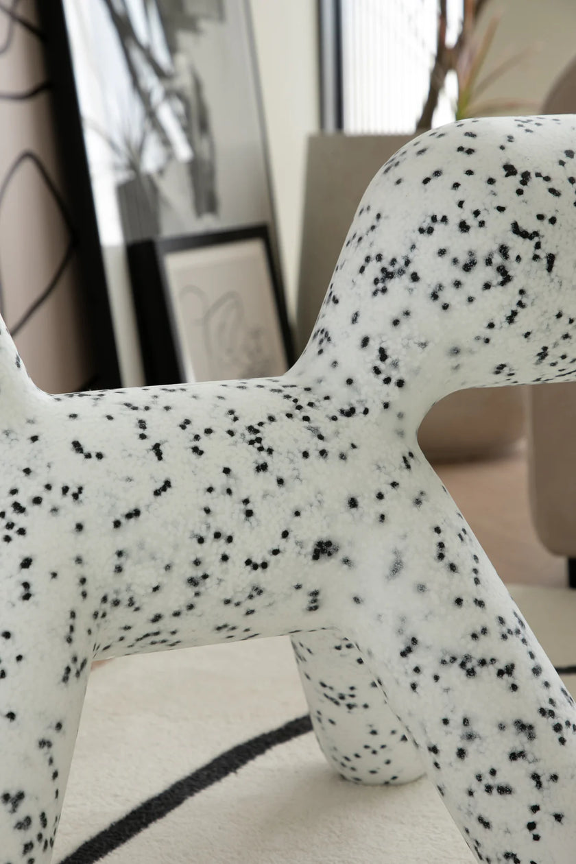 White toddler chair with black speckles in a room with a mirror and framed picture on the wall.