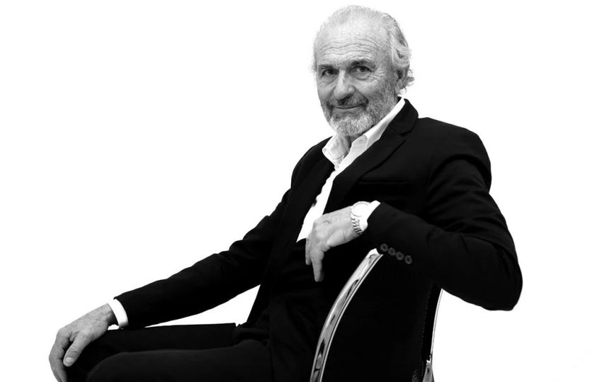 Black and white photo of a man in formal attire sitting on a chair.