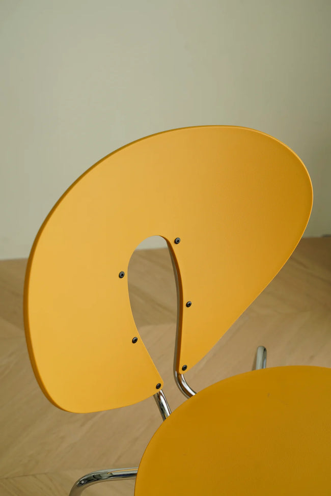 Yellow wooden metal chair with a unique design on a beige surface