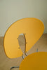 Yellow wooden metal chair with a unique design on a beige surface