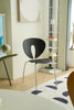 Modern black dining room chair in a room with a white wall and decorative elements.