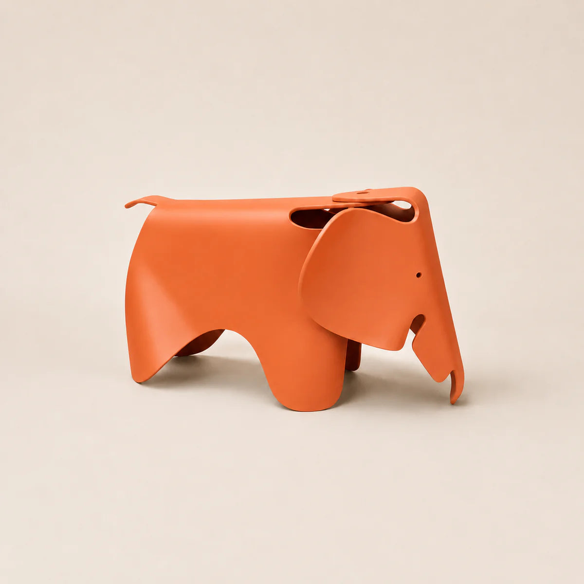 An orange elephant-shaped pp container with a matte finish, photographed on a clean, solid light beige background.