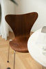 Wooden dining room chair with a white table in a room with light-colored floor and white walls