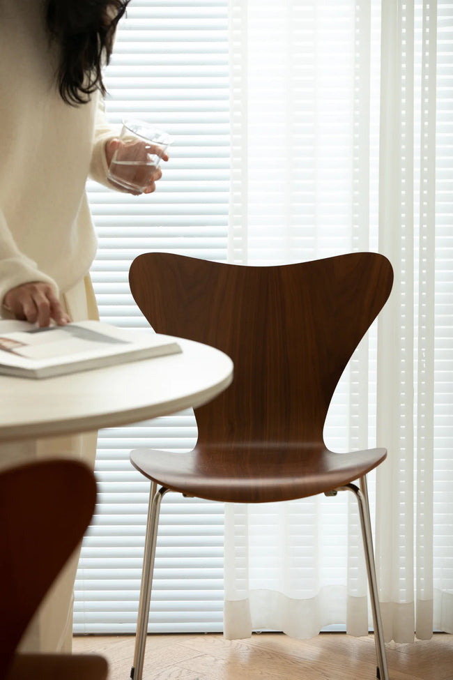 Wooden dining room chair in a room with a person and a table.