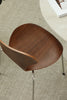 Wooden dining room chair with a curved backrest on a carpeted floor.