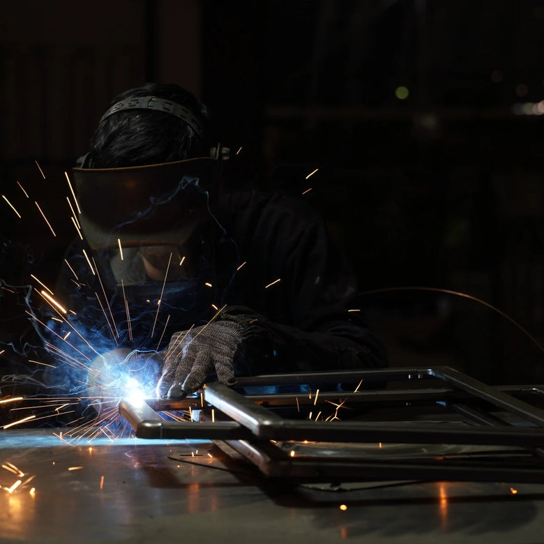 Person welding metal with sparks in a dark setting