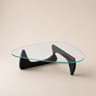 Modern glass coffee table with black curved legs on a beige background