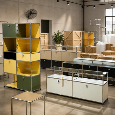 A showroom or warehouse interior displaying a modular storage furniture set. The set includes a tall, colorful modular cabinet on the left with yellow, green, and black compartments, and several long white, black, and green display/storage units with clear glass tops on the right and center.