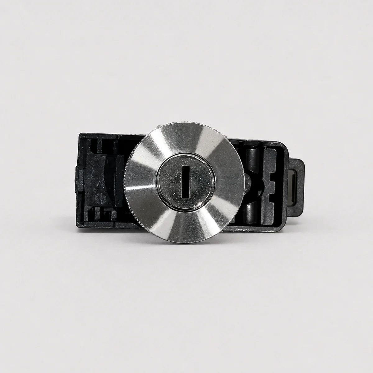 A close-up of a metallic silver key cylinder lock with a black plastic housing, shown against a plain light gray background.