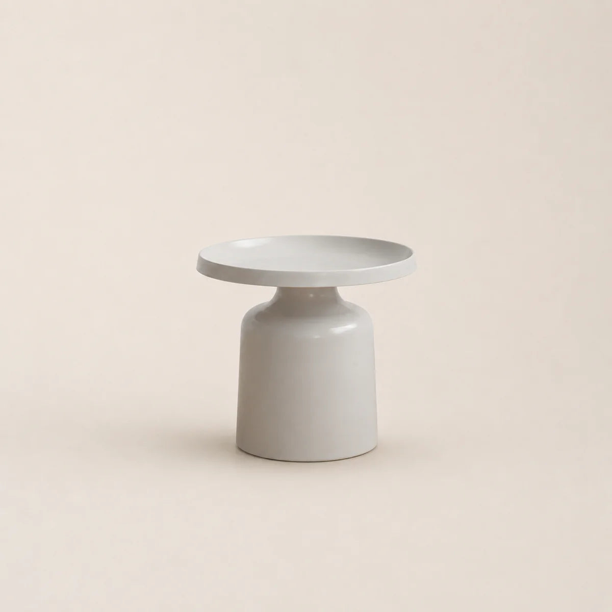 Minimalist ceramic table with a round top and cylindrical base on a beige background