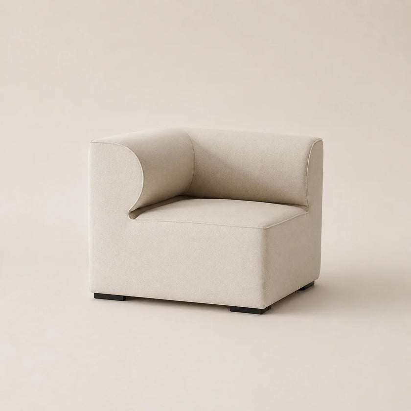 A modern low-profile accent chair upholstered in a light beige textured fabric, featuring a curved backrest and dark square feet, set against a solid warm beige background.