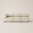 A modern three-seater modular sofa upholstered in a light beige textured fabric, shown against a matching minimalist beige background.