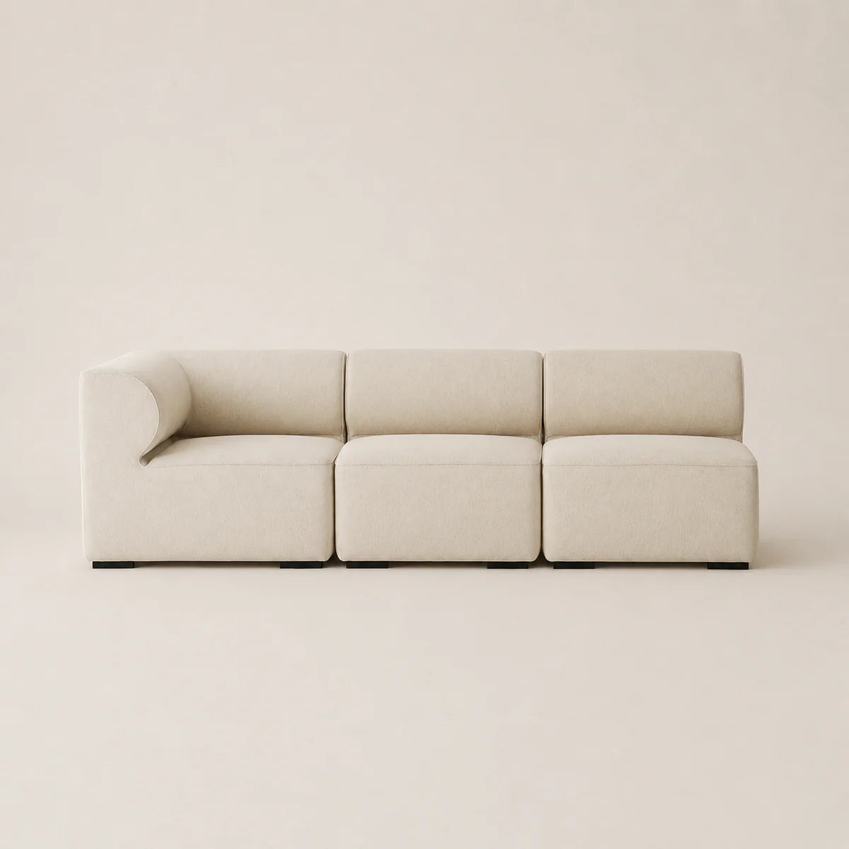 A modern three-seater modular sofa upholstered in a light beige textured fabric, shown against a matching minimalist beige background.