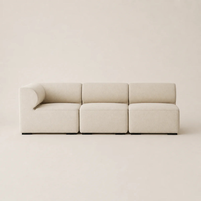 A modern three-seater modular sofa upholstered in a light beige textured fabric, shown against a matching minimalist beige background.