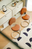 Three brown high chair with metal legs in front of a white dresser.