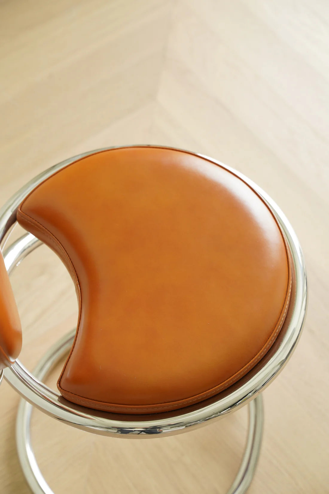 Brown leather high bar chair with metal frame on a light wooden floor