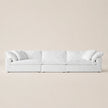 A modern white modular sofa with plush cushions and rolled arms, set against a minimalist beige background.