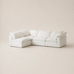 A modern white modular sectional sofa with thick cushions, shown in a minimalist studio setting with a warm beige background.