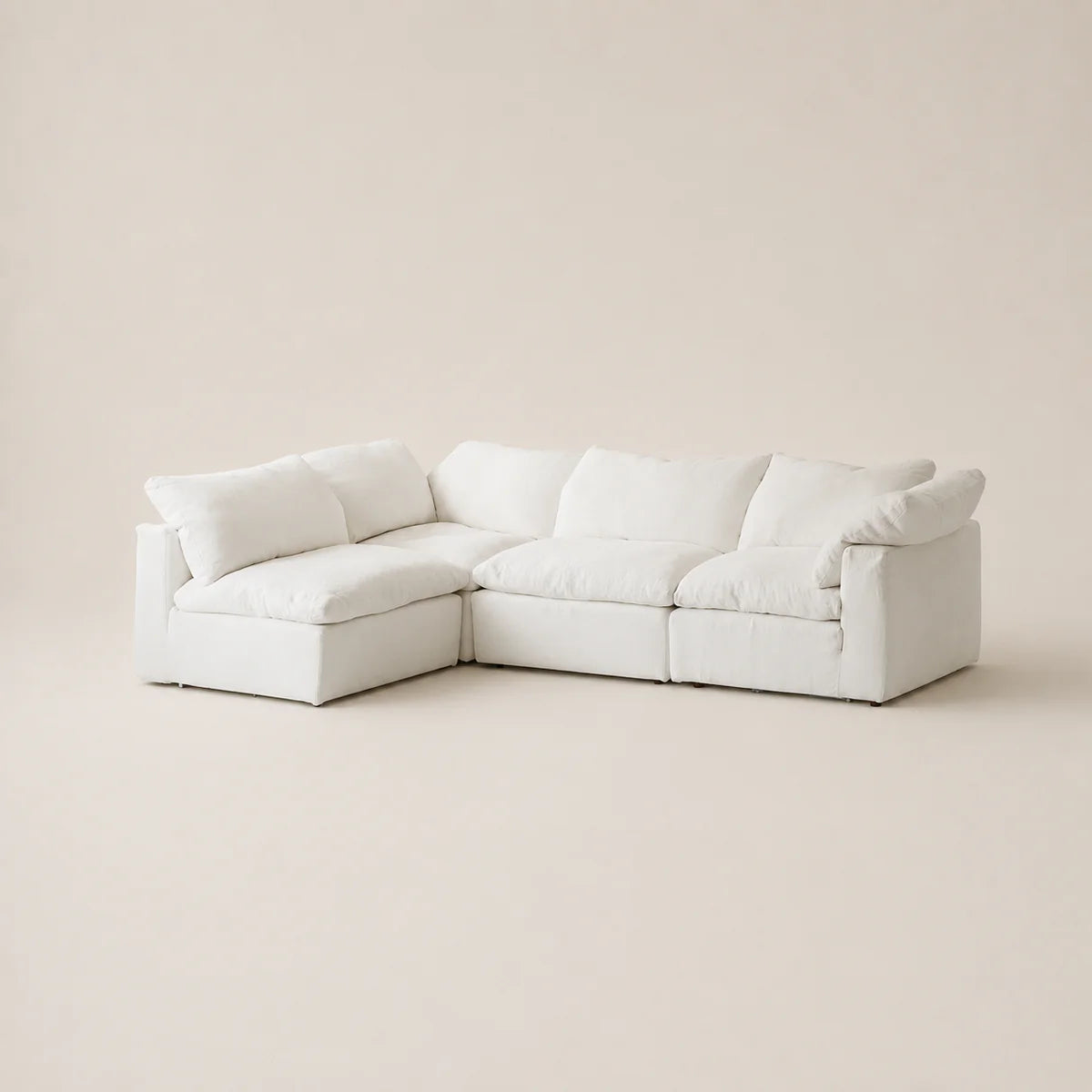 A modern white modular sectional sofa with thick cushions, shown in a minimalist studio setting with a warm beige background.
