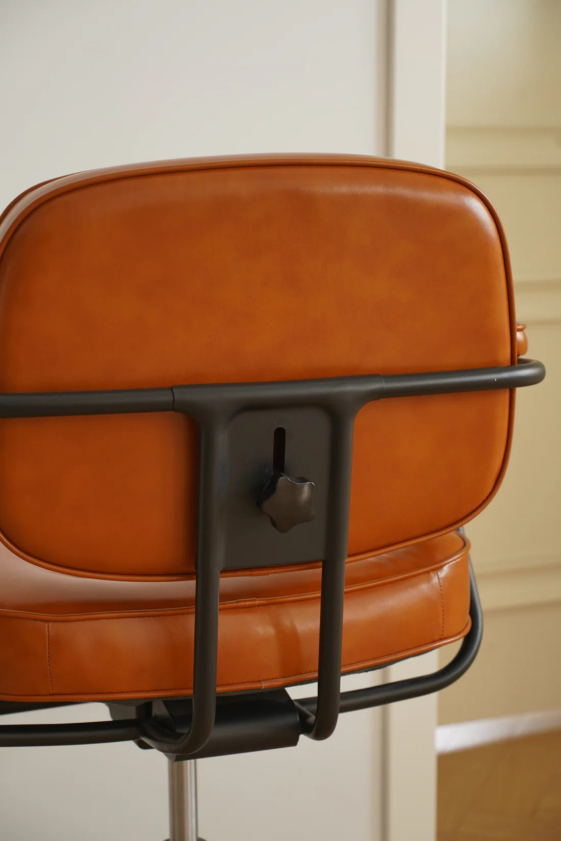 Brown leather office chair with black metal frame against a neutral background