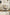 Beige office desk swivel arm chair in a room with a record player and abstract art on the wall.