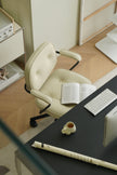 Beige office chair in a modern office setting with a desk, keyboard, and book.