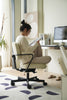 Women sitting at a desk chair reading a book in a modern office setting